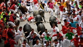 In this July 14, 2017, file photo, revellers fall next to Miura's fighting bulls during the running of the bulls at the San Fermin Festival, in Pamplona, northern Spain.