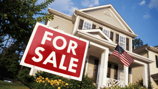 For Sale sign on the front yard of a home.