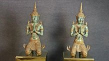 Two bronze Buddha statues with hands together, appearing to be praying.