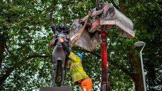 A contractor uses ropes to secure the statue "A Surge of Power (Jen Reid) 2020" by artist Marc Quinn, which had been installed on the site of the fallen statue of the slave trader Edward Colston, as they prepare to remove and load it into a recycling and skip hire lorry, in Bristol, Thursday, July 16, 2020. The sculpture of protestor Jen Reid was installed without the knowledge or consent of Bristol City Council and was removed by the council 24 hours later.