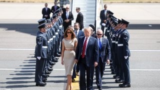 U.S. President Donald Trump, center, U.S. First Lady Melania Trump, left, and Woody Johnson, U.S. ambassador to the United Kingdom, make their way to Marine One after arriving nat London Stansted Airport in Stansted, U.K., on Thursday, July 12, 2018. Trump will avoid London as much as possible as he's whisked off on a tour of prime British real estate to keep him away from protesters during his U.K. visit.