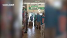 A crowd of shoppers looks out the doors of a store