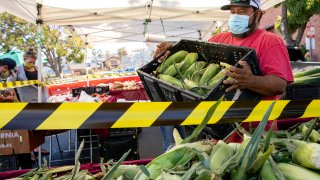 Aldo Perez of Jacob's Farms wears a mask while restocking corn at their booth at the Benicia Farmer's Market in Benicia, Calif. Thursday, July 30, 2020.