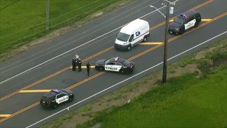 Police officers stand outside their cruisers on a road in Ventnor, New Jersey, as a mail truck is stopped nearby.