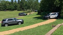 Police SUVs park at Fischer's Park in Montgomery County, Pennsylvania, as crime scene tape surrounds a grassy area.