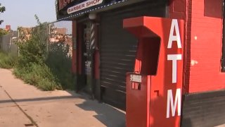 A red ATM that was blown up stands next to a West Philadelphia barber shop.