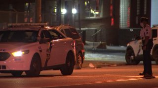 A Philadelphia Police Department officer stands across a police cruiser at the site of a hit-and-run crash.