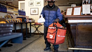 A DoorDash Inc. delivery person places an order into an insulated bag at Chef Geoff’s restaurant in Washington, D.C.