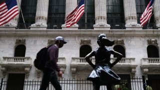 People walk by the New York Stock Exchange (NYSE) on May 18, 2020 in New York City.