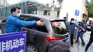 A car that's part of a convoy carrying the World Health Organization team of researchers arrives at the Hubei Provincial Hospital