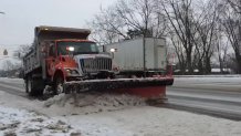 A snow plow clears snow from one side of a Delaware road as a big rig drives by on the other side.