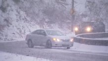 A silver sedan nearly spins out as it rounds a turn in East Falls, Philadelphia. A black van approaches the turn behind the sedan.