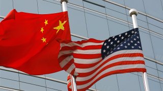 The national flags of the U.S. and China waving outside a building.