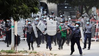 In this Feb. 20, 2021, file photo, police charge forward to disperse protesters in Mandalay, Myanmar. Security forces in Myanmar ratcheted up their pressure against anti-coup protesters Saturday, using water cannons, tear gas, slingshots and rubber bullets against demonstrators and striking dock workers in Mandalay, the nation's second-largest city.
