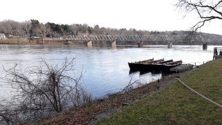 A deck sticks out from a grassy bank and overtop the waters of the Delaware River.