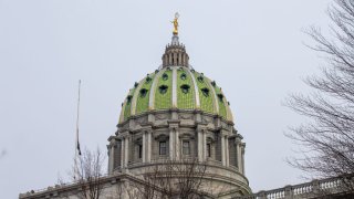 The dome of the Pennsylvania State Capitol is seen against a gray sky.
