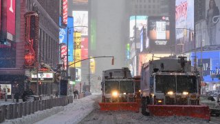 Snowplows drive through Times Square during a winter storm