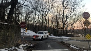 A Philadelphia police SUV is parked behind two stop signs in the city's Fairmount Park. Behind the vehicle is ground covered in snow, as well as leafless trees.
