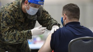 A member of the U.S. Armed Forces administers a COVID-19 vaccine to a police officer at a FEMA community vaccination center on March 2, 2021 in Philadelphia,
