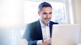 Businessman working on a laptop smiling.