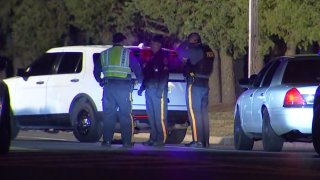 Three police officers commiserate at the site of a fatal hit-and-run in Burlington Township, New Jersey.