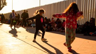 Children play as families of asylum seekers wait outside the El Chaparral border crossing port as they wait to cross into the United States in Tijuana, Baja California state, Mexico on February 19, 2021.