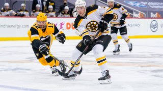 Boston Bruins Center Charlie Coyle (13) passes the puck while Pittsburgh Penguins Left Wing Zach Aston-Reese (12) defends during the third period in the NHL game between the Pittsburgh Penguins and the Boston Bruins on April 25, 2021, at PPG Paints Arena in Pittsburgh, PA.