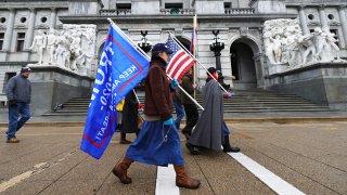 People with a Trump flag and an American flag in front of Pennsylvania's Capitol building