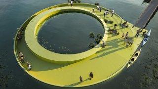 This digital rendering shows people walking atop a ring-like art installation called the "FloatLab" on Philadelphia's Schuylkill River