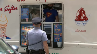 A Philadelphia police officer stands in front of a truck and orders ice cream.