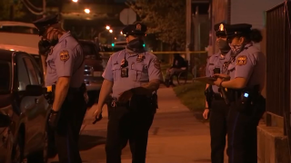 Philadelphia police officers stand at the scene where a 10-year-old boy was grazed by a bullet.