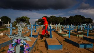 A gravedigger walks among graves of COVID-19 victims at the Nossa Senhora Aparecida cemetery in Manaus, Amazonas state, Brazil, on April 29, 2021.