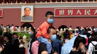 In this May 3, 2021, file photo, a man and child wearing masks visit Tiananmen Gate near the portrait of Mao Zedong in Beijing. China’s ruling Communist Party is looking at allowing easing birth limits further to allow couples to have three children instead of two in response to the population's rising age, a state news agency said Monday, May 31, 2021.