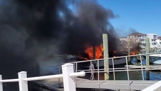 Flames and black smoke billow from a boat at a harbor in Wildwood, New Jersey.