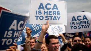 Demonstrators in support of U.S. President Barack Obama’s health-care law, the Affordable Care Act (ACA), hold up ‘ACA is Here to Stay’ signs after the U.S. Supreme Court ruled 6-3 to save Obamacare tax subsidies outside the Supreme Court in Washington, D.C. June 25, 2015.