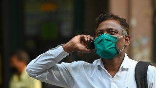 A pedestrian speaks on a mobile phone as he looks at share prices on a digital broadcast outside the Bombay Stock Exchange (BSE) in Mumbai on November 10, 2020.