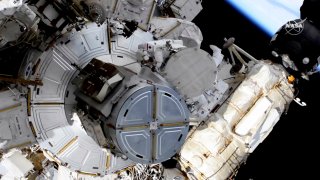 In this image taken from NASA video, French astronaut Thomas Pesquet, top center, and NASA astronaut Shane Kimbrough venture out on a spacewalk Wednesday, June 16, 2021, to outfit the International Space Station with powerful, new solar panels to handle the growing electrical demands from upcoming visitors.