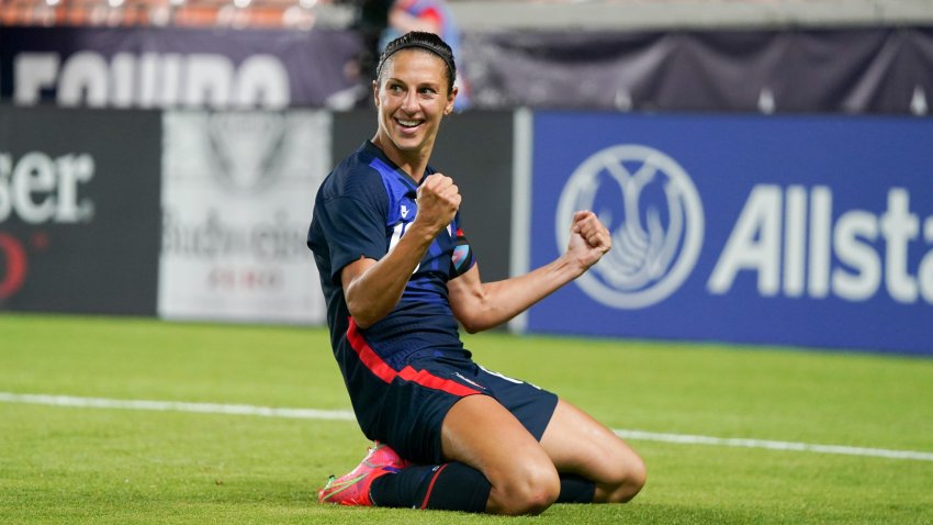 Carli Lloyd smiling and celebrating a goal on her knees