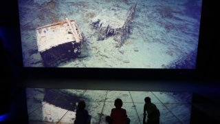 BELFAST, NORTHERN IRELAND - MARCH 27: Visitors look at a projection showing images of the wreck of the Titanic on the seabed at the Titanic Belfast visitor attraction on March 27, 2012 in Belfast, Northern Ireland. The Titanic Belfast Experience is a new £90 million visitor attraction opening on March 31, 2012. One hundred years ago the maiden voyage of the ill-fated passenger liner Titanic sank after hitting an iceberg in the Atlantic on the night of April 14, 1911 with the loss of 1517 lives.