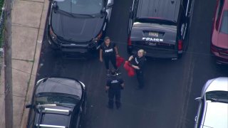 An aerial view shows three police officers holding red bags on a street near where a 14-year-old boy was shot to death in Wilmington.