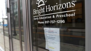 A sign in the window of Bright Horizons Early Education and Preschool notes that the child care center is closed on Apr. 2, 2020 in the Seaport District of Boston.