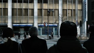 Pedestrians wait for traffic signals to change outside a securities firm in Tokyo, Japan, on Wednesday, Feb. 17, 2021.