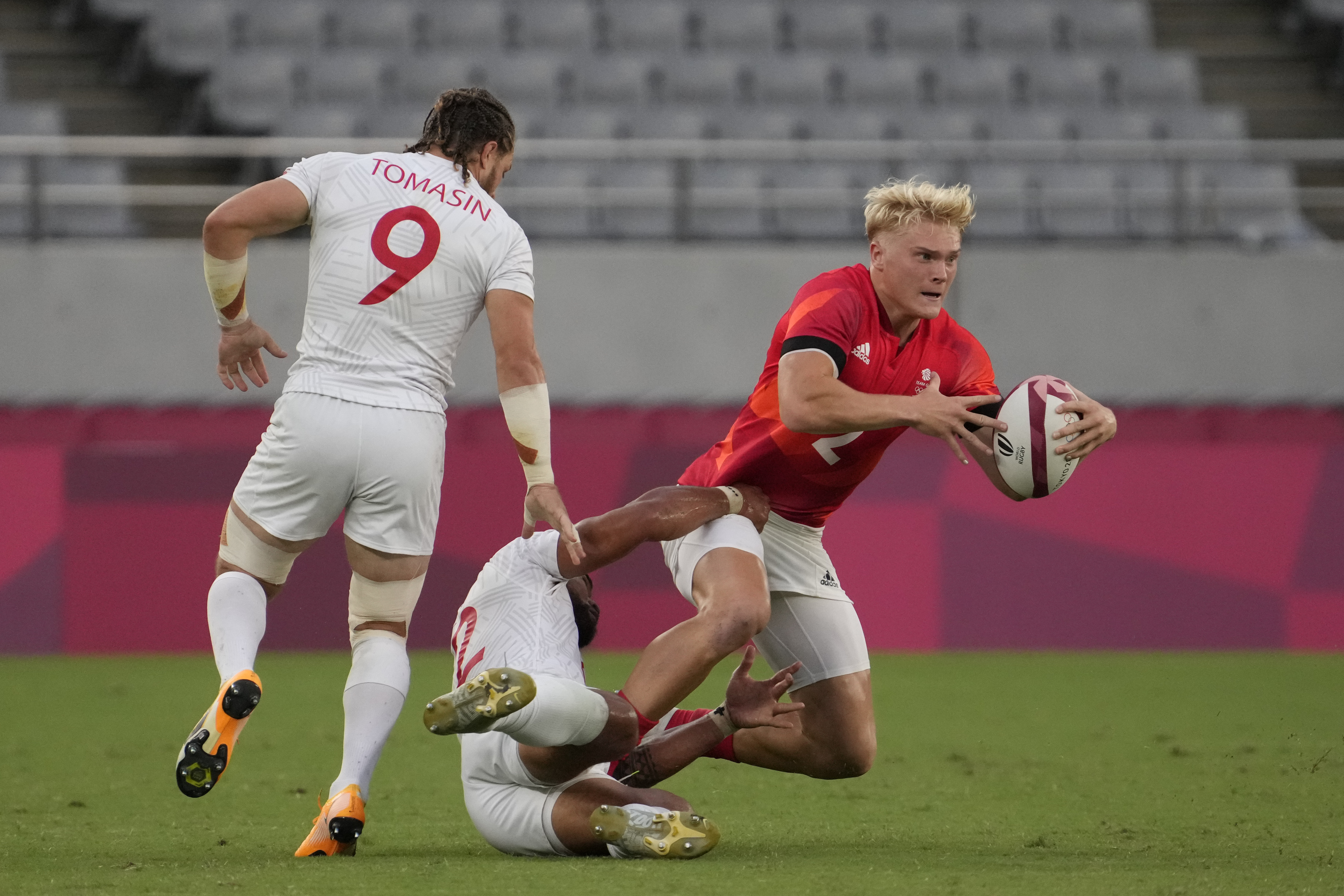 Britain's Ben Harris, right, is tackled by Martin Iosefo of the United States as Steve Tomasin of the United States pursues, in their men's rugby sevens quarterfinal match at the 2020 Summer Olympics, Tuesday, July 27, 2021 in Tokyo, Japan.