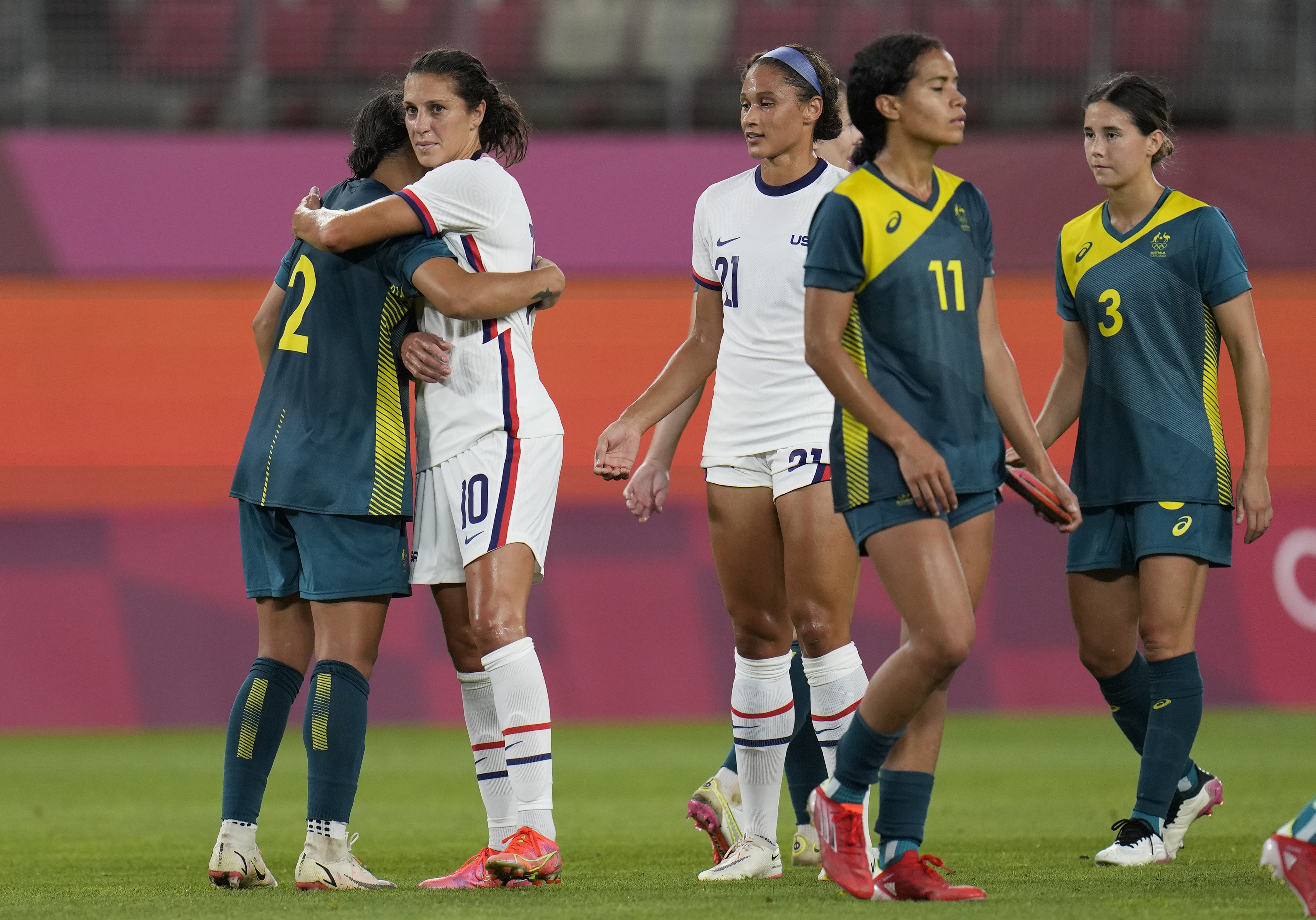 United States' Carli Lloyd, 2nd left, and Australia's Sam Kerr embrace each other at the end of their women's soccer match at the 2020 Summer Olympics, Tuesday, July 27, 2021, in Kashima, Japan. The game ended in a 0-0 draw.