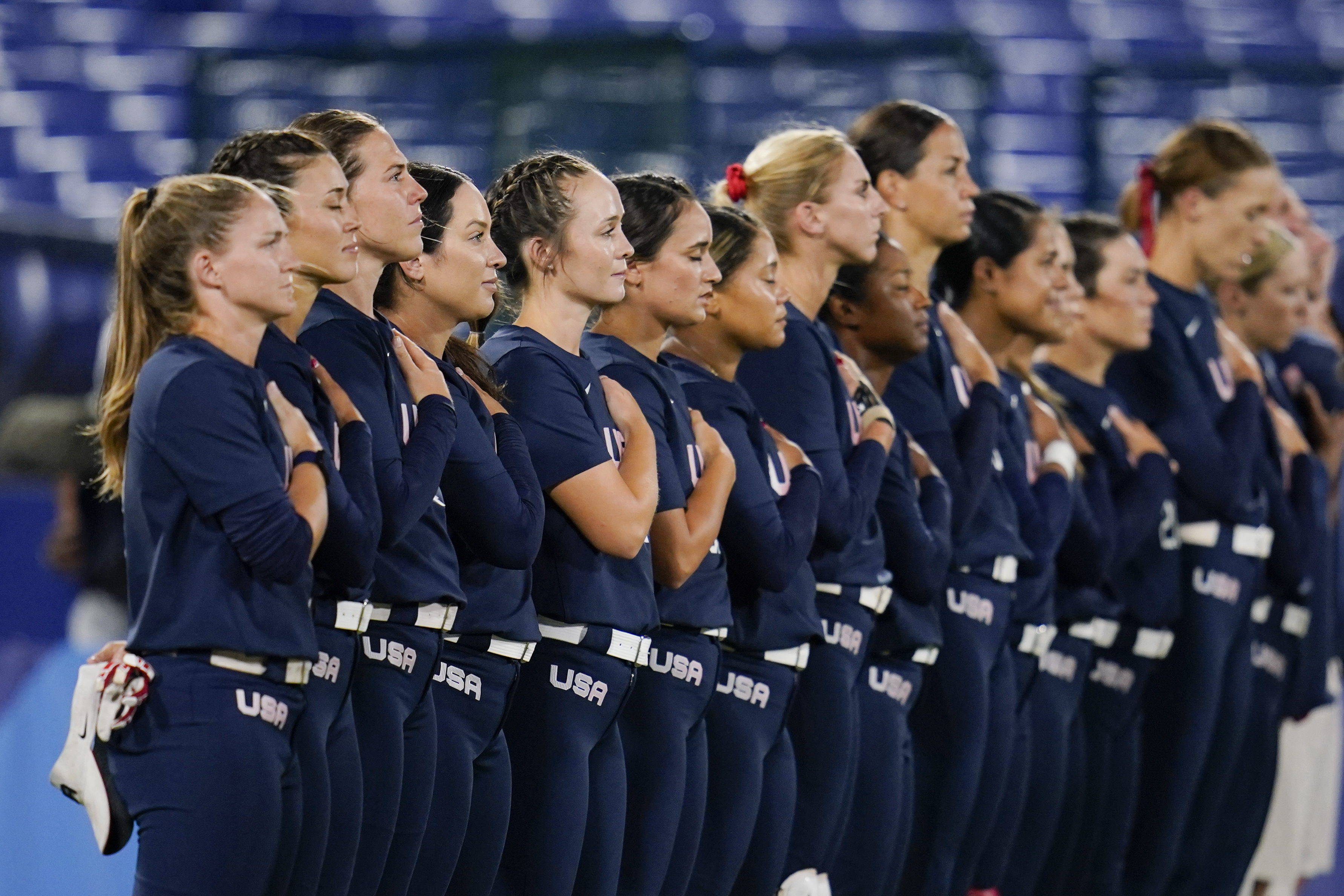 Members of team United States stand for their national anthem prior to a softball game against Japan at the 2020 Summer Olympics, Tuesday, July 27, 2021, in Yokohama, Japan.