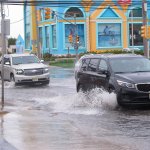 This Oct. 11, 2019 photo shows cars kicking up spray while driving through a flooded intersection at the entrance to Long Beach Island in Ship Bottom, N.J. With the highest tides of the year expected to arrive in New Jersey during the week of May 24, 2021, the state is launching a campaign to have residents document tidal flooding in their neighborhood and upload photos to a web site.