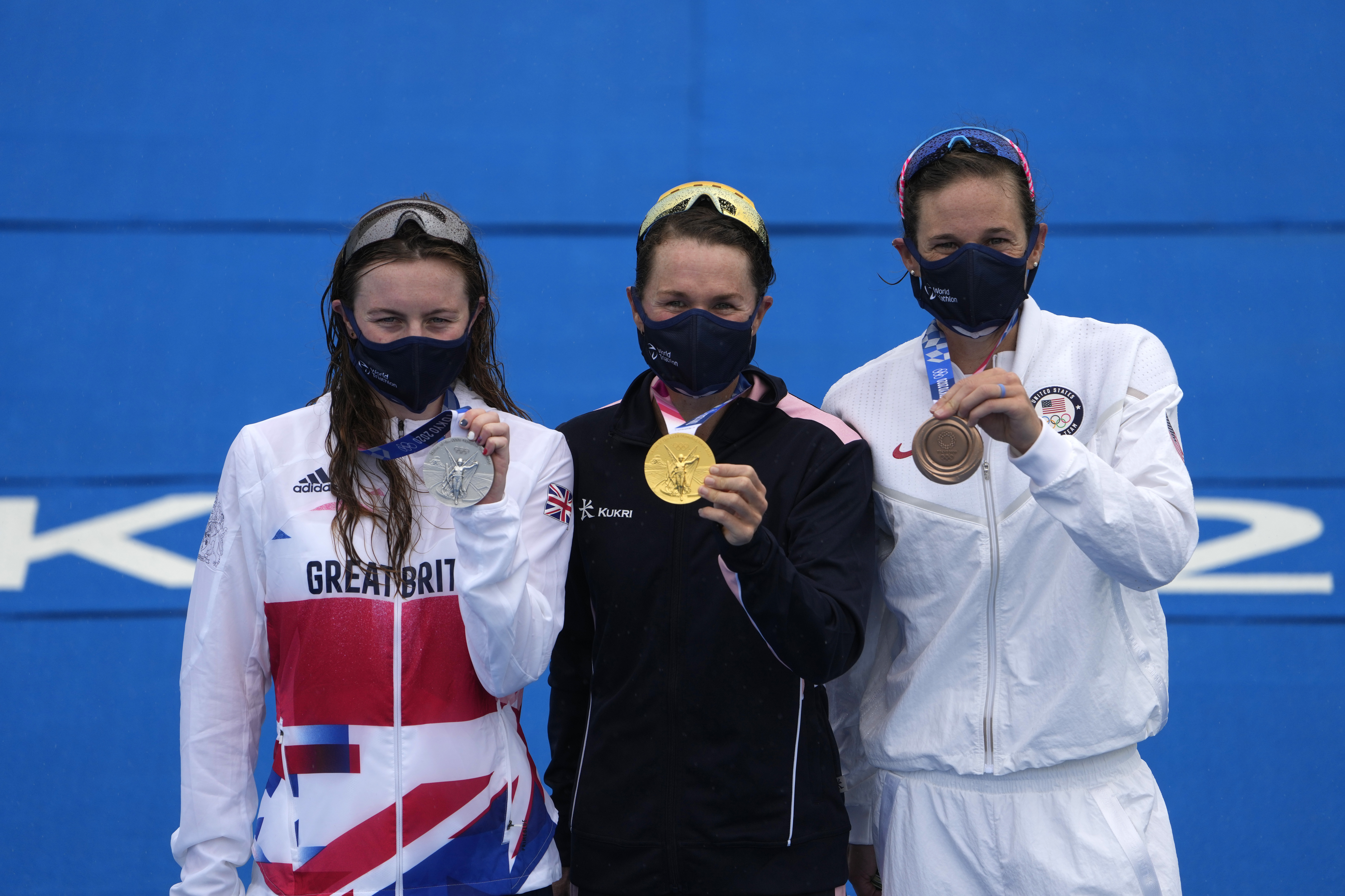 Gold medal winner Flora Duffy of Bermuda, center, hugs silver medalist Georgia Taylor-Brown of Great Britain, left, and Katie Zaferes of The United States during a medal ceremony for the women's individual triathlon competition at the 2020 Summer Olympics on July 27, 2021, in Tokyo, Japan.