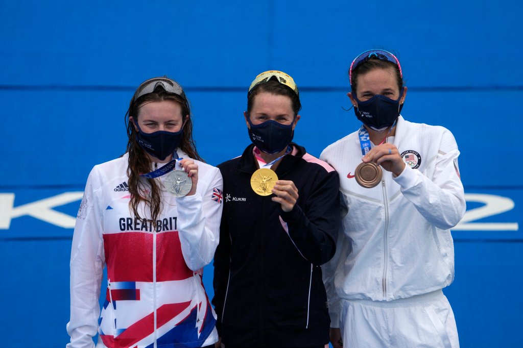 Gold medal winner Flora Duffy of Bermuda, center, hugs silver medalist Georgia Taylor-Brown of Great Britain, left, and Katie Zaferes of The United States during a medal ceremony for the women's individual triathlon competition at the 2020 Summer Olympics on July 27, 2021, in Tokyo, Japan.