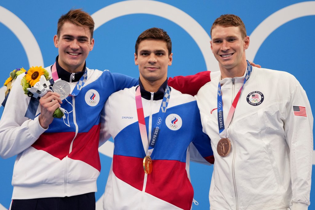 Gold medalist Evgeny Rylov, centre, of the Russian Olympic Committee stands with compatriot and silver medalist Kliment Kolesnikov, left, and bronze medalist Ryan Murphy of the United States after the men's 100-meter backstroke final at the 2020 Olympics on July 27, 2021, in Tokyo, Japan.