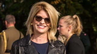 Carla Sands smiles while wearing sunglasses